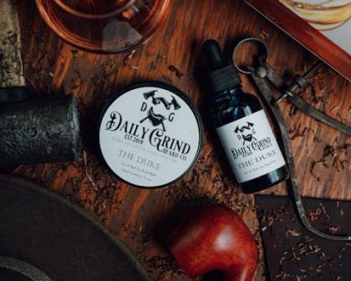 Detailed rustic flat lay of Daily Grind beard balm and oil on wooden surface.