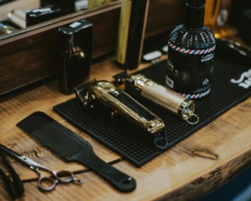Close-up of barber tools on a wooden table including clippers and comb in a Polish barbershop.